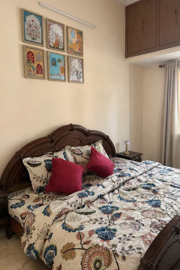 Bedroom with framed miniature paintings above the bed